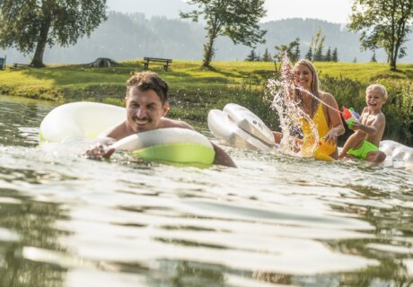Wasserspaß am Badesee Reitdorf. Am Bild sieht man eine Familie beim Plantschen im Wasser.