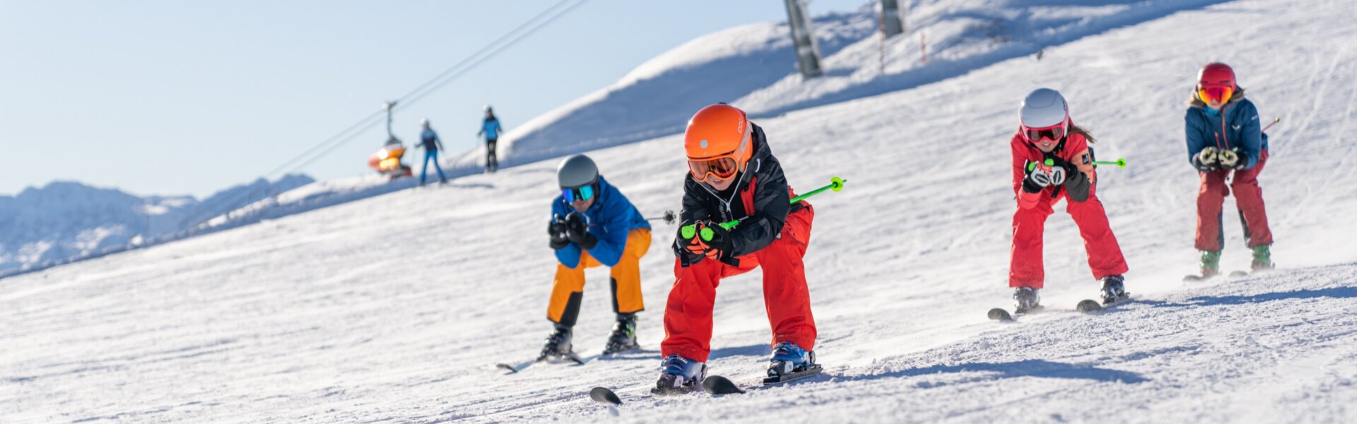Pistenskifahren in Flachau. Am Bild sieht man: eine Familie die in der Hocke hinunterfährt. Im Hintergrund erkennt man die Skistation Starjet 3.