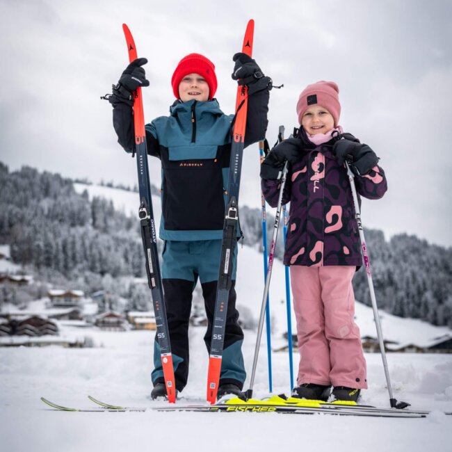 Zwei Kinder mit Langlaufski und Skistöcken im Schnee