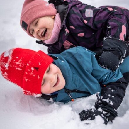 Zwei Kinder lachen und spielen im Schnee