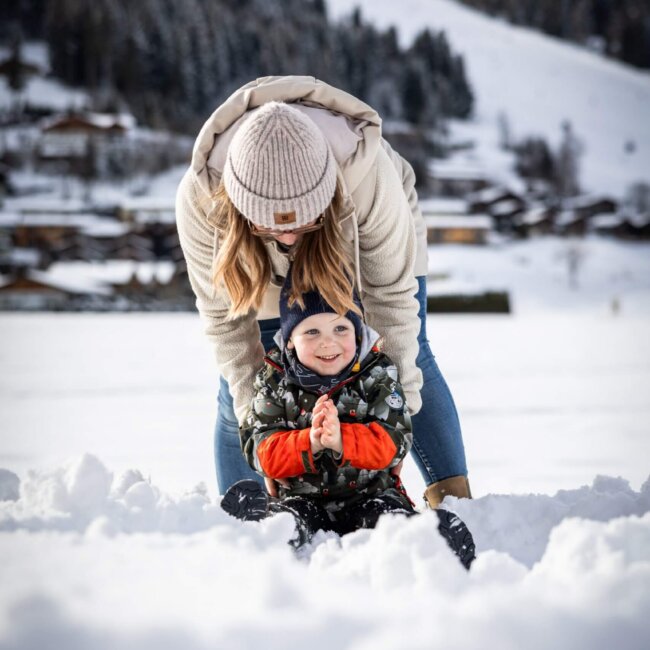 Mama und Kind haben Spaß im Schnee