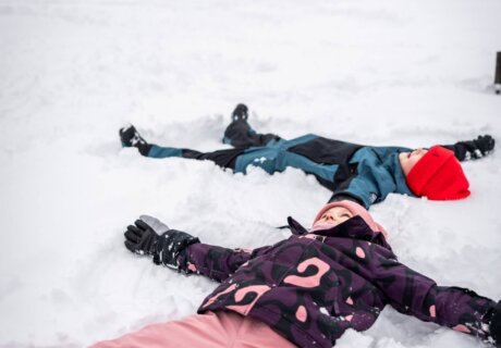 Kinder machen einen Schneeengel im Schnee